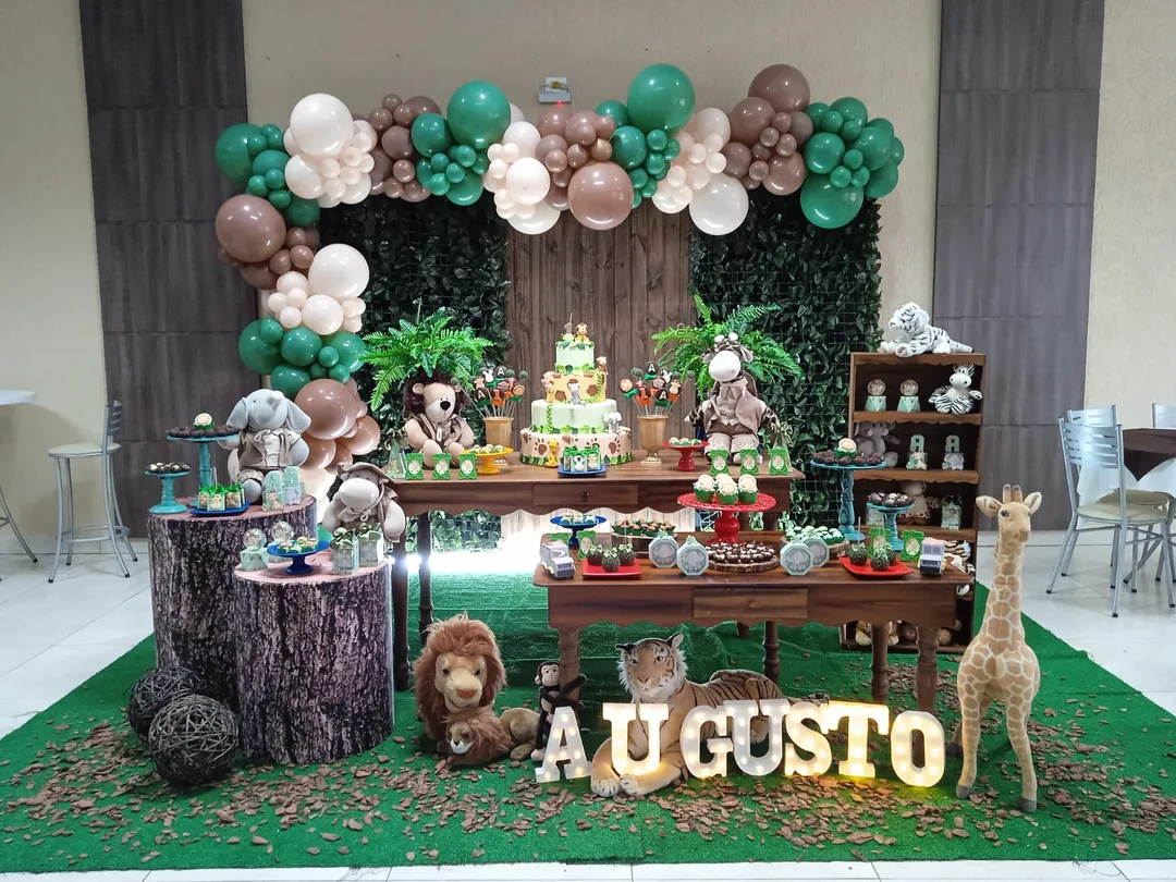 Decoração de safári com parede de folhagem, mesa rústica e bolo de dois andares
